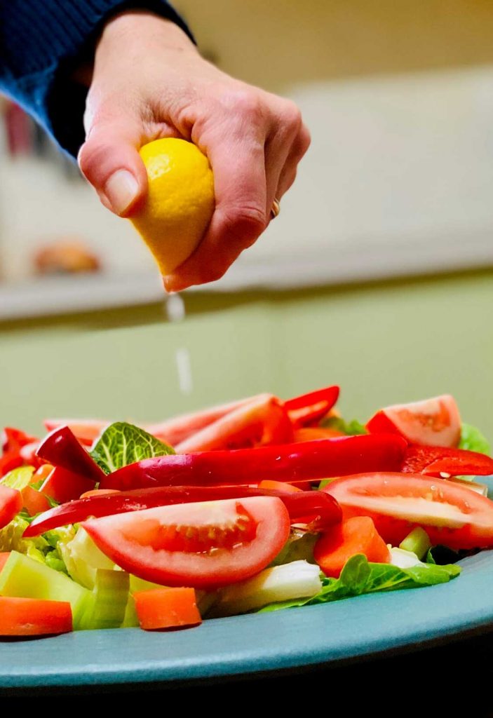 Squeezing lemon juice over a salad | Border Park Kitchen